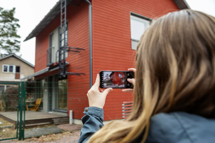 På bilden fotograferar en person ett egethemshus med sin smartphone.